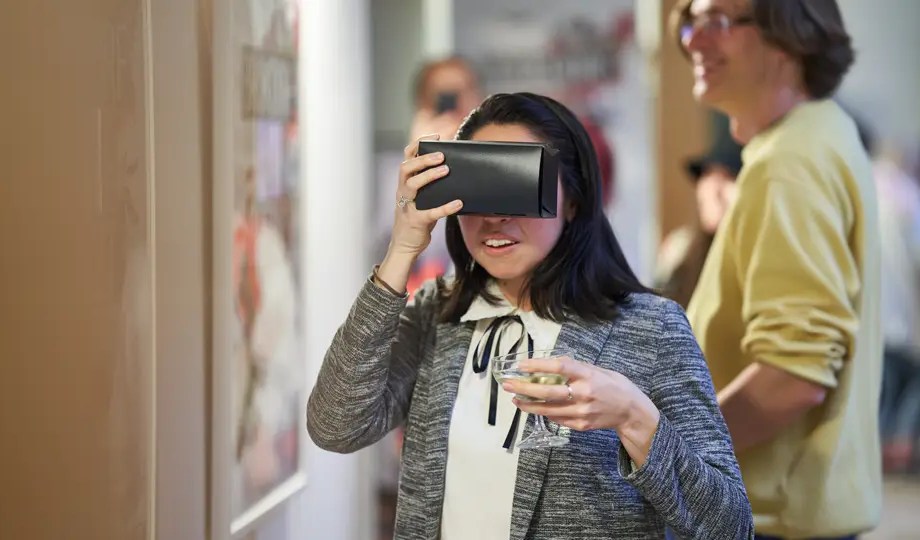 a woman having 3D VR glasses in her hand and a drink